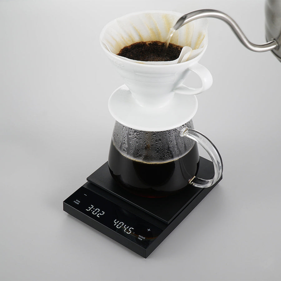 Coffee brewing process with a white pour-over coffee filter and glass carafe on a Hario Polaris Coffee Scale (Black)