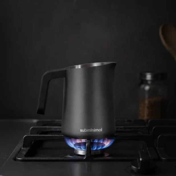 Subminimal FlowTip Milk Jug 450ml, Black with Handle being heated on a gas hob