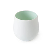 White ceramic Tajimi cup with a light green interior on a white background