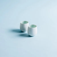 Two white ceramic cups on a light blue background