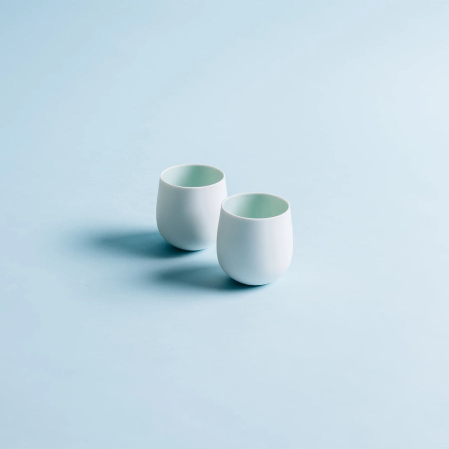 Two white ceramic cups on a light blue background