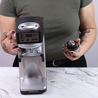 Person holding a Baratza Sette 270Wi Coffee Grinder and the removable burrs on a marble surface.
