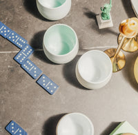 Blue dominoes and white Tajimi cups on a gray surface