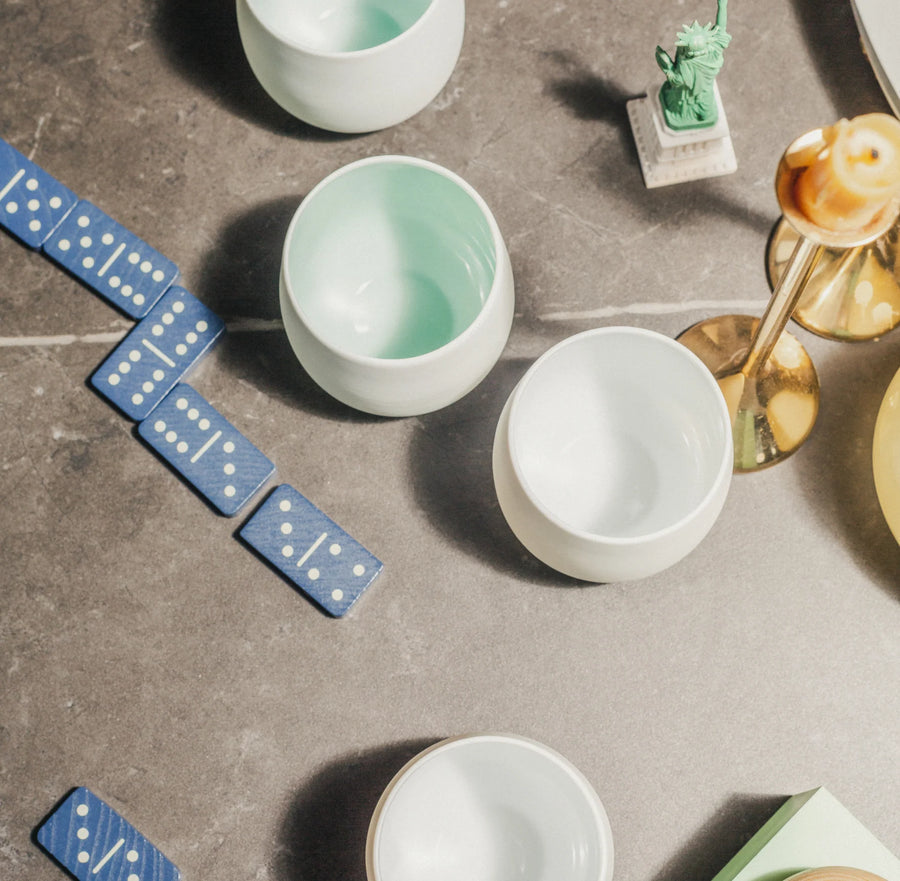 Blue dominoes and white Tajimi cups on a gray surface